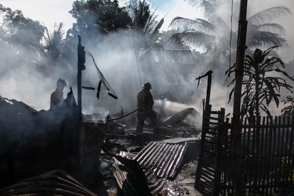 silhouette-of-fireman-holding-hose-942560 Brave firefighters battle a blaze amidst thick smoke in an outdoor setting.