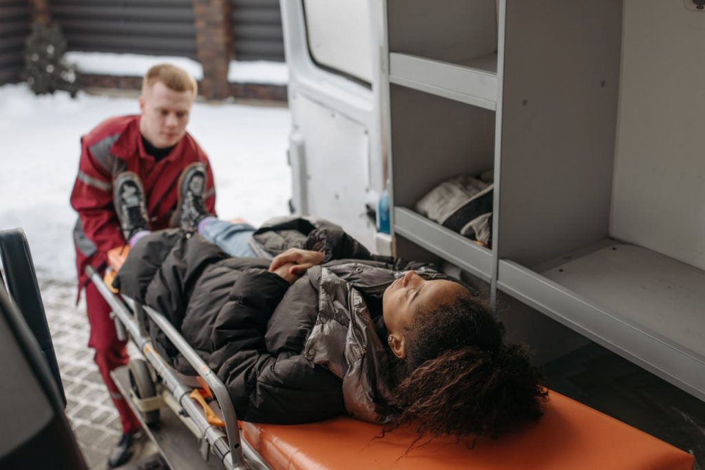 woman-on-a-stretcher-6754168 Emergency medical technicians assisting a patient onto a stretcher and into an ambulance.